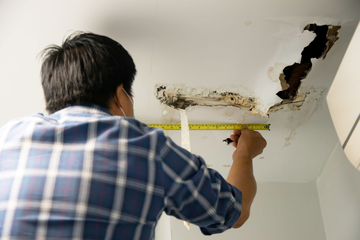guy measuring ceiling damage hail damage roof repair